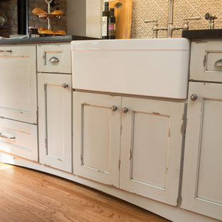 Inspiration för ett litet vintage svart svart kök, med en rustik diskho, beige skåp, granitbänkskiva, beige stänkskydd, stänkskydd i keramik, integrerade vitvaror, mellanmörkt trägolv, brunt golv och släta luckor