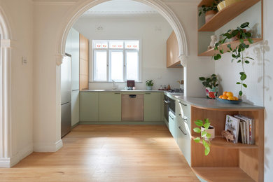 Design ideas for a mid-sized modern u-shaped eat-in kitchen in Sydney with an undermount sink, flat-panel cabinets, green cabinets, recycled glass benchtops, white splashback, matchstick tile splashback, stainless steel appliances, no island and grey benchtop.
