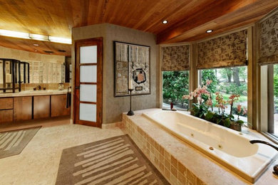 Design ideas for a mid-sized modern master bathroom in Other with flat-panel cabinets, dark wood cabinets, a drop-in tub, grey walls, travertine floors, a drop-in sink, tile benchtops and beige floor.