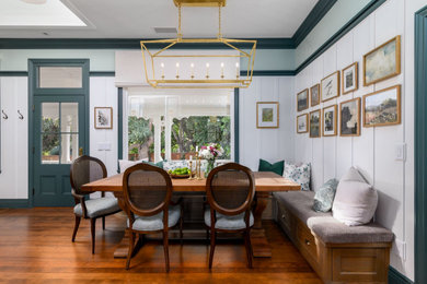 Example of an ornate medium tone wood floor, brown floor and wall paneling dining room design in Santa Barbara with green walls