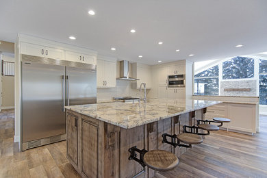 Example of a large country l-shaped vinyl floor and gray floor eat-in kitchen design in Calgary with a farmhouse sink, shaker cabinets, white cabinets, granite countertops, white backsplash, ceramic backsplash, stainless steel appliances, an island and gray countertops