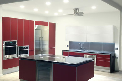 Photo of a mid-sized contemporary eat-in kitchen in Hawaii with an undermount sink, flat-panel cabinets, red cabinets, granite benchtops, metallic splashback, porcelain splashback, stainless steel appliances and porcelain floors.