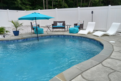 Ejemplo de piscina clásica de tamaño medio a medida en patio trasero con losas de hormigón