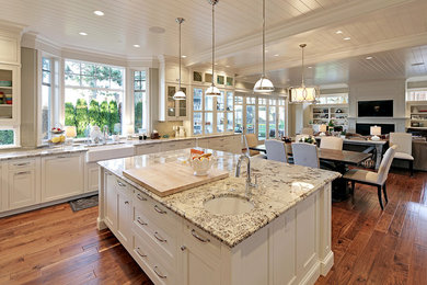 This is an example of a large transitional l-shaped eat-in kitchen in Seattle with a farmhouse sink, shaker cabinets, white cabinets, granite benchtops, beige splashback, subway tile splashback, stainless steel appliances, medium hardwood floors and with island.