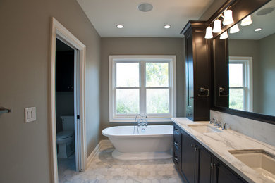 Bathroom in Milwaukee with an undermount sink, recessed-panel cabinets, black cabinets, marble benchtops, a freestanding tub, an open shower, a two-piece toilet, white tile and ceramic tile.