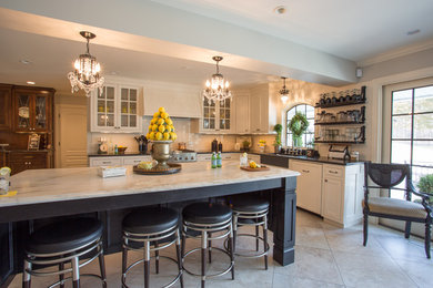Open concept kitchen - huge traditional l-shaped porcelain tile and beige floor open concept kitchen idea in Other with a farmhouse sink, shaker cabinets, white cabinets, marble countertops, white backsplash, subway tile backsplash, stainless steel appliances and an island