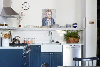 Urban l-shaped dark wood floor and brown floor eat-in kitchen photo in New York with a farmhouse sink, shaker cabinets, blue cabinets, white backsplash, subway tile backsplash, stainless steel appliances, no island and gray countertops