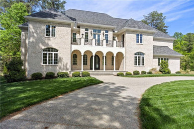 Huge traditional beige three-story brick exterior home idea in Richmond
