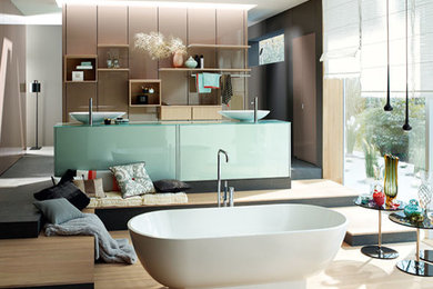 Cette image montre une très grande salle de bain principale design en bois clair avec un placard à porte affleurante, une baignoire indépendante, un carrelage multicolore, des carreaux de céramique, un mur multicolore, un sol en ardoise, un lavabo posé et un plan de toilette en verre.