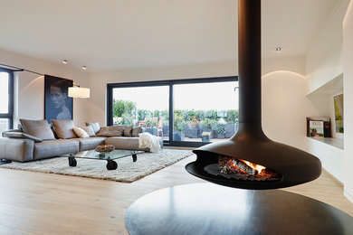 Photo of a large contemporary open concept living room in Frankfurt with white walls, light hardwood floors, a hanging fireplace and no tv.