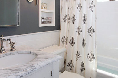 Photo of a small traditional bathroom in Boston with an undermount sink, shaker cabinets, white cabinets, marble benchtops, a drop-in tub, a shower/bathtub combo, a two-piece toilet, white tile, grey walls and marble floors.