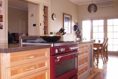 Mid-sized contemporary galley eat-in kitchen in Melbourne with a drop-in sink, shaker cabinets, light wood cabinets, quartz benchtops, red splashback, glass sheet splashback, coloured appliances, light hardwood floors and with island.