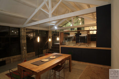 Exemple d'une grande salle de séjour mansardée ou avec mezzanine industrielle avec un mur blanc, sol en béton ciré, un poêle à bois, aucun téléviseur et un sol gris.