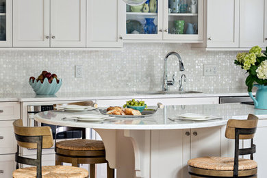 This is an example of a mid-sized beach style galley separate kitchen in Boston with an undermount sink, shaker cabinets, white cabinets, quartzite benchtops, white splashback, mosaic tile splashback, stainless steel appliances, medium hardwood floors, with island and brown floor.