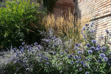 Esempio di un giardino xeriscape shabby-chic style esposto in pieno sole di medie dimensioni in estate con un pendio, una collina o una riva e ghiaia