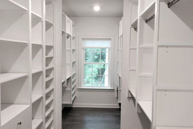 Design ideas for a large walk-in wardrobe in Philadelphia with flat-panel cabinets, white cabinets and dark hardwood flooring.
