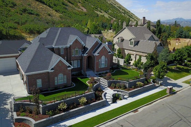 Huge traditional red two-story brick house exterior idea with a hip roof and a shingle roof