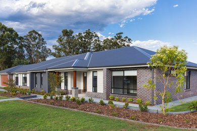 Large country one-storey grey house exterior in Brisbane with wood siding, a gable roof and a metal roof.