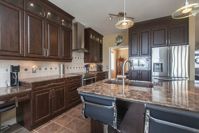Inspiration for a mid-sized timeless l-shaped ceramic tile eat-in kitchen remodel in Toronto with an undermount sink, raised-panel cabinets, dark wood cabinets, quartz countertops, beige backsplash, ceramic backsplash, stainless steel appliances and an island