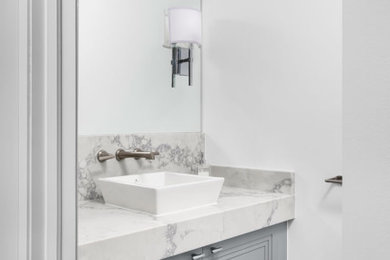 Powder room - small contemporary white tile and marble tile porcelain tile and gray floor powder room idea in Toronto with recessed-panel cabinets, gray cabinets, white walls, a vessel sink, marble countertops and white countertops