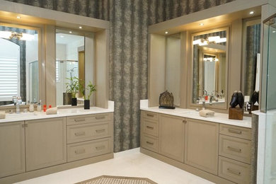 Example of a large master ceramic tile and white floor corner shower design in Miami with recessed-panel cabinets, beige cabinets, multicolored walls, an undermount sink, solid surface countertops and a hinged shower door