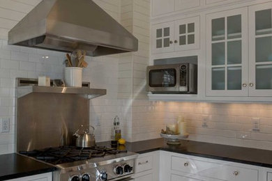 Eat-in kitchen - small contemporary u-shaped light wood floor eat-in kitchen idea in Denver with stainless steel appliances, a single-bowl sink, recessed-panel cabinets, white cabinets, solid surface countertops, white backsplash, ceramic backsplash and no island