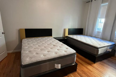 Imagen de dormitorio principal minimalista de tamaño medio con paredes multicolor, suelo de madera clara, suelo beige y panelado