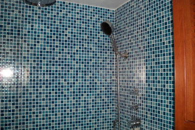 Example of a mid-sized transitional master blue tile, gray tile and glass tile ceramic tile alcove shower design in Miami with medium tone wood cabinets, a two-piece toilet and blue walls