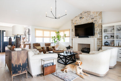 Design ideas for a country open concept family room in Los Angeles with white walls, light hardwood floors, a standard fireplace, a wall-mounted tv and vaulted.