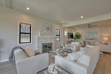 Example of a large trendy open concept light wood floor and gray floor living room design in San Diego with a music area, gray walls, a standard fireplace, a stone fireplace and a media wall