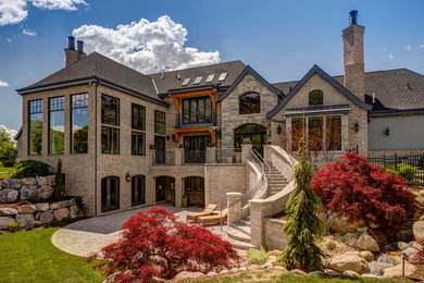 Inspiration for a huge timeless beige three-story brick house exterior remodel in Salt Lake City with a hip roof and a shingle roof