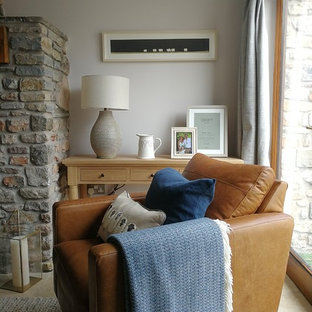 Foto de salón cerrado, de estilo de casa de campo, pequeño, con paredes grises, suelo de travertino, estufa de leña, marco de chimenea de piedra, pared multimedia y suelo beige