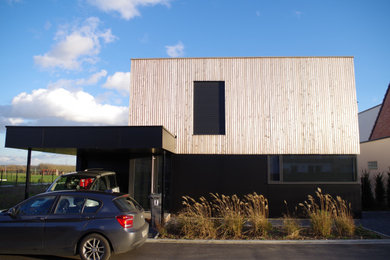 Idée de décoration pour une grande façade de maison noire minimaliste en bardage à clin à deux étages et plus avec un revêtement mixte, un toit plat, un toit mixte et un toit gris.