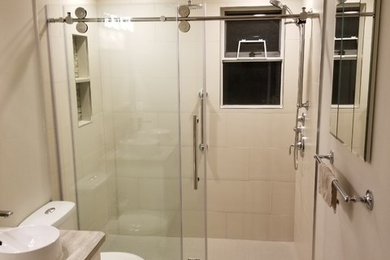 Inspiration for a contemporary beige tile and ceramic tile vinyl floor bathroom remodel in Other with white cabinets, a two-piece toilet, a vessel sink, laminate countertops and beige countertops