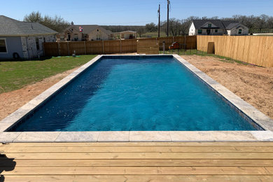 Imagen de piscina alargada contemporánea de tamaño medio rectangular en patio trasero con paisajismo de piscina, privacidad y adoquines de hormigón