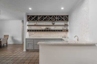 Example of a mid-sized classic u-shaped wet bar design in Houston with an undermount sink, recessed-panel cabinets, gray cabinets, granite countertops, multicolored backsplash, granite backsplash and multicolored countertops
