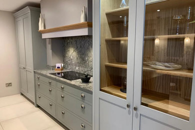 Contemporary galley kitchen in West Midlands with shaker cabinets, grey cabinets, grey splashback, an island and grey worktops.