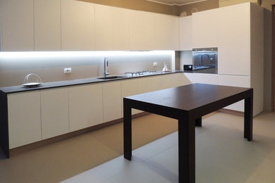 Foto di una cucina moderna di medie dimensioni con lavello integrato, ante bianche, top in quarzite, paraspruzzi beige, elettrodomestici in acciaio inossidabile, pavimento con piastrelle in ceramica, nessuna isola, pavimento beige e top marrone