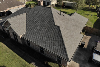 Inspiration for a timeless one-story house exterior remodel in Houston with a hip roof, a shingle roof and a black roof