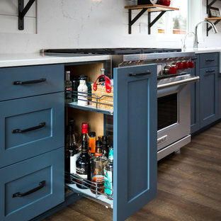 Mid-sized farmhouse kitchen pantry ideas - Inspiration for a mid-sized farmhouse single-wall medium tone wood floor and brown floor kitchen pantry remodel in Portland with a farmhouse sink, shaker cabinets, gray cabinets, quartz countertops, stainless steel appliances, an island, white backsplash and stone tile backsplash