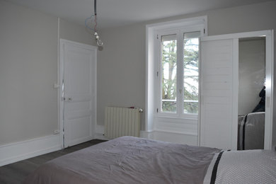 Ejemplo de habitación de invitados de tamaño medio sin chimenea con paredes grises, suelo laminado, suelo marrón y boiserie