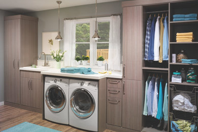 This is an example of a mid-sized transitional single-wall dedicated laundry room in Columbus with an undermount sink, flat-panel cabinets, medium wood cabinets, solid surface benchtops, grey walls, medium hardwood floors and a side-by-side washer and dryer.