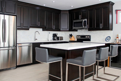 Mid-sized transitional l-shaped porcelain tile eat-in kitchen photo in Toronto with an undermount sink, flat-panel cabinets, dark wood cabinets, quartz countertops, gray backsplash, porcelain backsplash, stainless steel appliances and an island