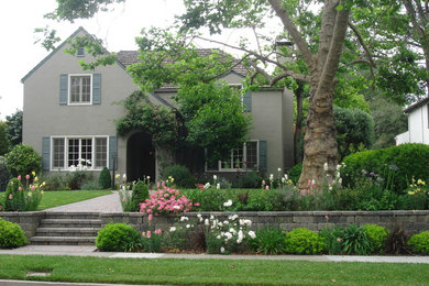 Photo of a large traditional front yard partial sun garden in Los Angeles with a retaining wall and brick pavers.