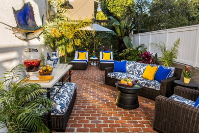 Photo of a mid-sized tropical backyard patio in Los Angeles with brick pavers.