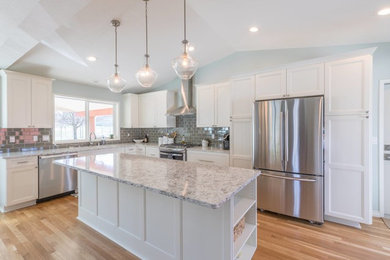 This is an example of a mid-sized transitional l-shaped eat-in kitchen in Seattle with recessed-panel cabinets, white cabinets, quartz benchtops, grey splashback, ceramic splashback, stainless steel appliances, multiple islands, an undermount sink and medium hardwood floors.