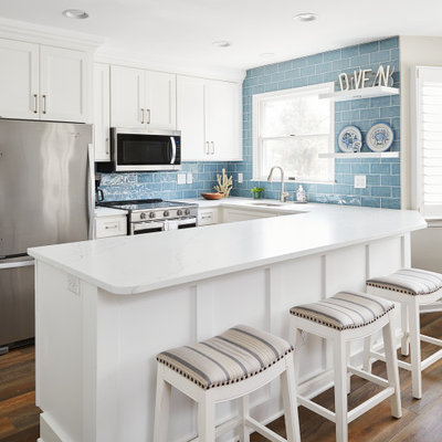 Example of a small beach style galley eat-in kitchen design in Other with white cabinets, stainless steel appliances and a peninsula
