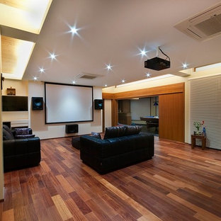 Cette image montre une grande salle de cinéma design ouverte avec un mur jaune, sol en stratifié et un écran de projection.