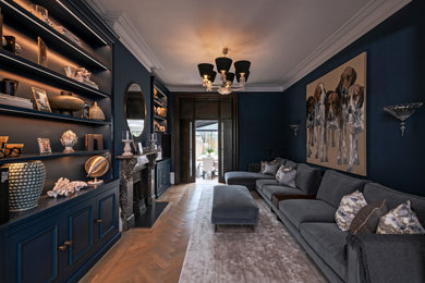 Large contemporary enclosed living room in London with a reading nook, blue walls, light hardwood flooring, a standard fireplace, a stone fireplace surround, a wall mounted tv, brown floors and a chimney breast.