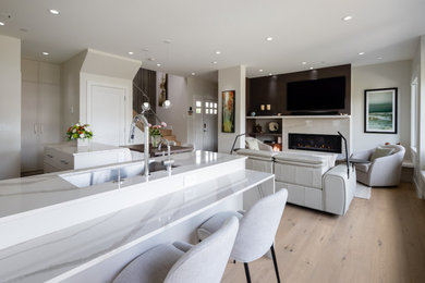 Example of a small l-shaped light wood floor and beige floor open concept kitchen design in Vancouver with an undermount sink, flat-panel cabinets, gray cabinets, quartz countertops, gray backsplash, stone slab backsplash, paneled appliances, a peninsula and gray countertops